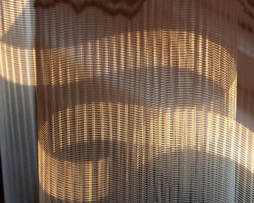 Soft sunlight filtering through sheer curtains into a home office